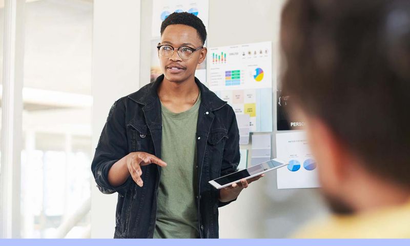 A man talks in a meeting while holding a tablet.