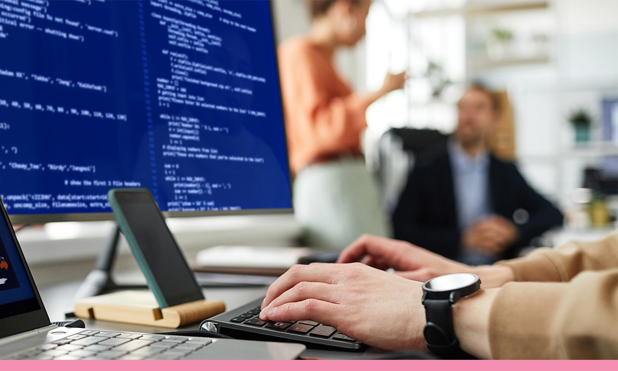 A person types lines of code on a computer.