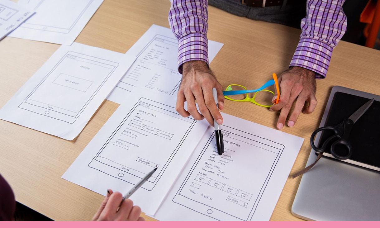 Two people discuss the user experience of an app on a tablet.