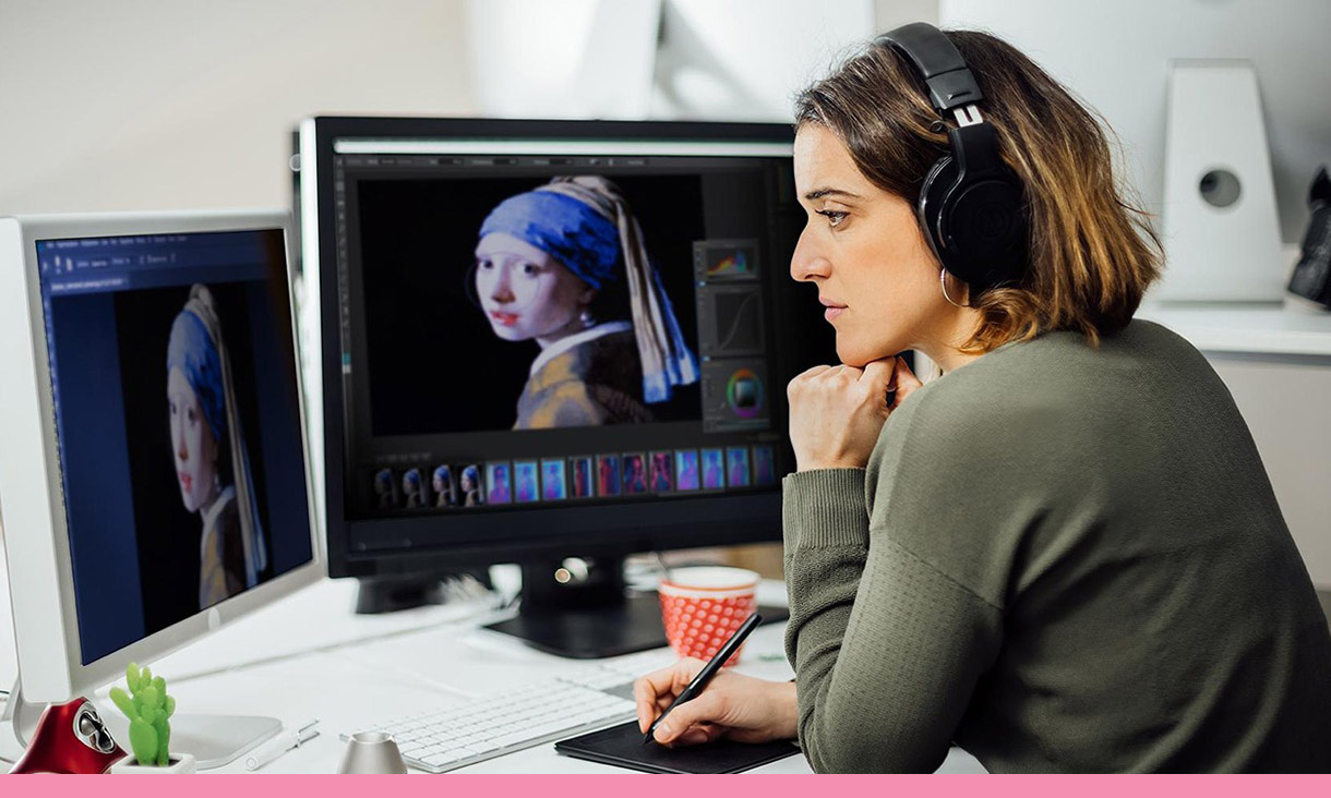 A woman draws digitally while wearing headphones.