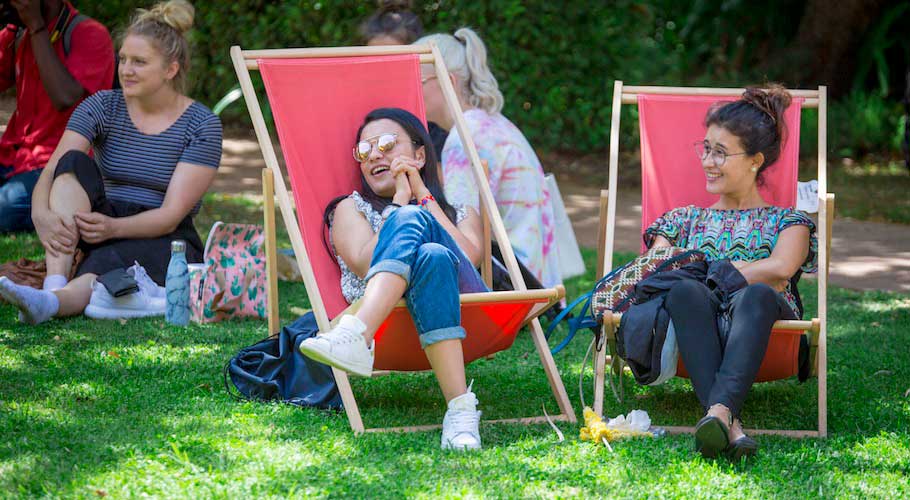 Two students relax on deck chairs on campus.