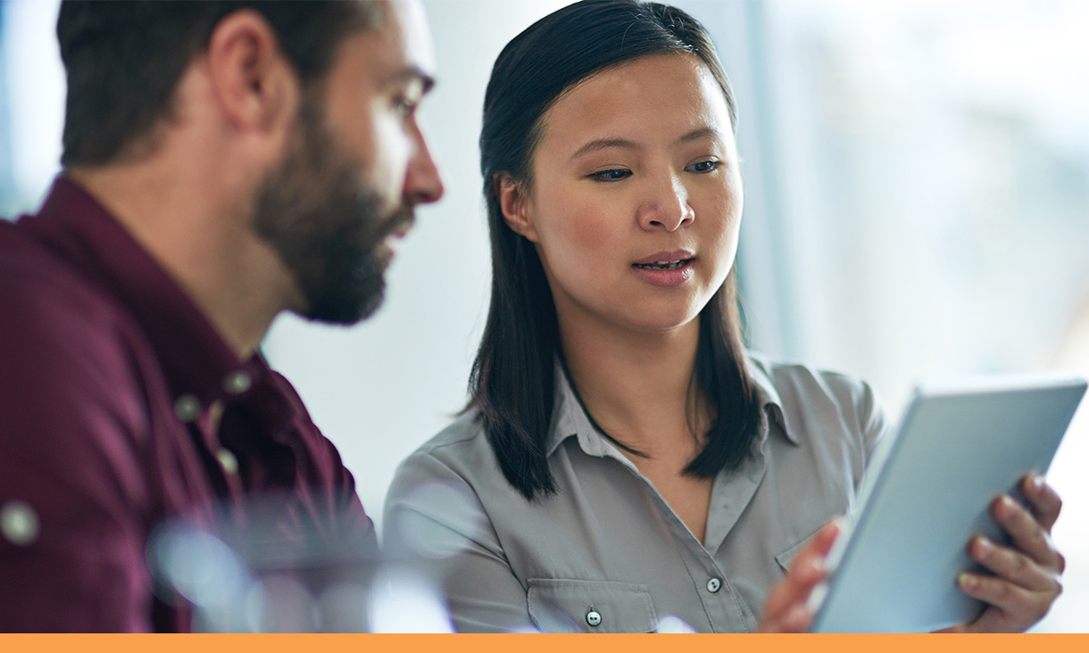 A woman shows her coworker something on her tablet.
