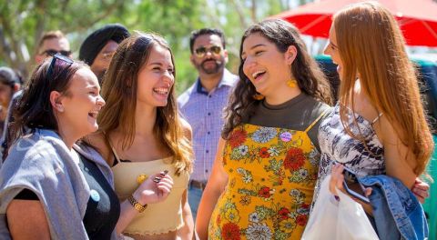 Four students laugh together at an event at the City Campus.