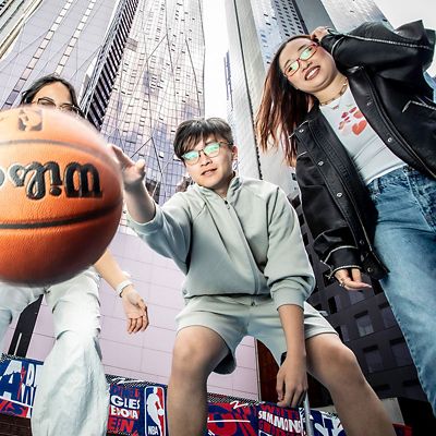 Three students playing basketball on a college campus.