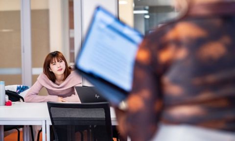 International student sitting in a classroom with a laptop on a table.