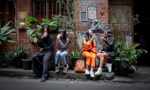 A group of four students sitting on a Street at the RMIT Melbourne city campus.