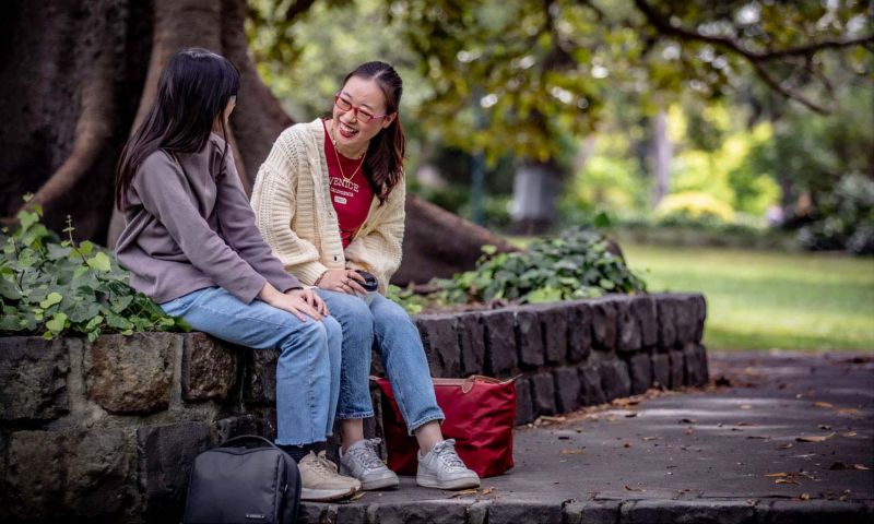 Two international students sitting in a park talking
