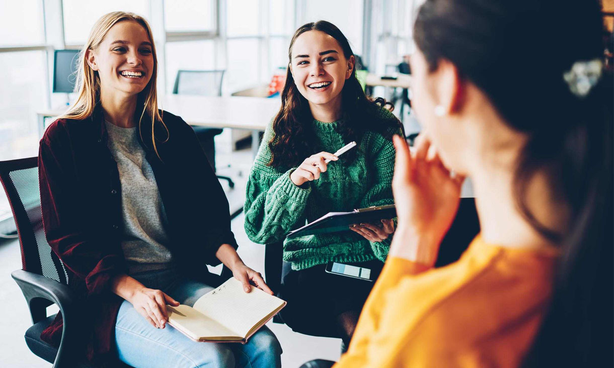 Three coworkers in an office talking to each other