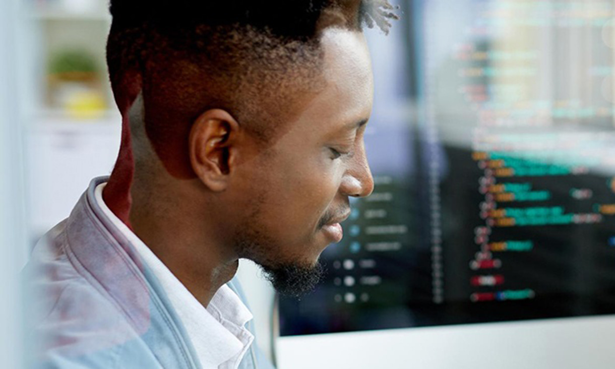 A man with a blurry screen of code in the background.