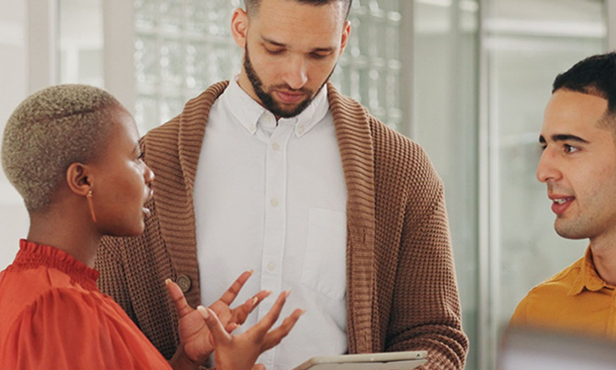 A woman and two men talking to each other in an office. 