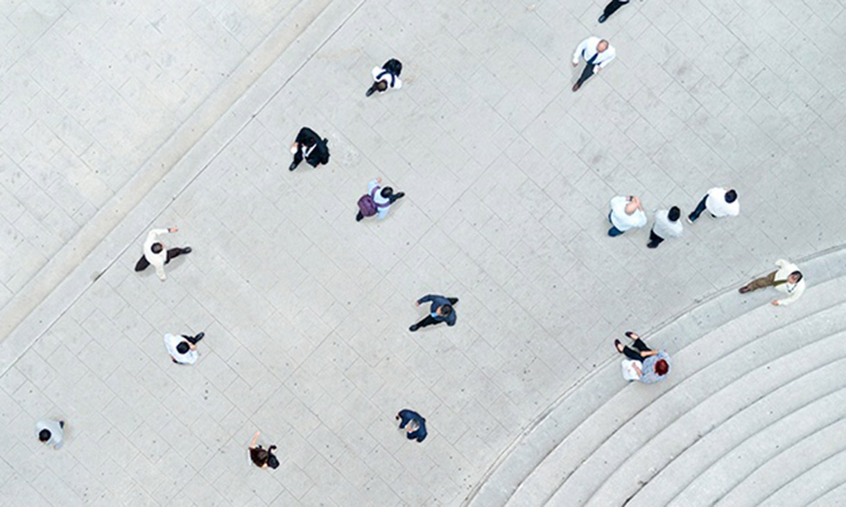Birds eye view of a crowd of people walking across pavement.