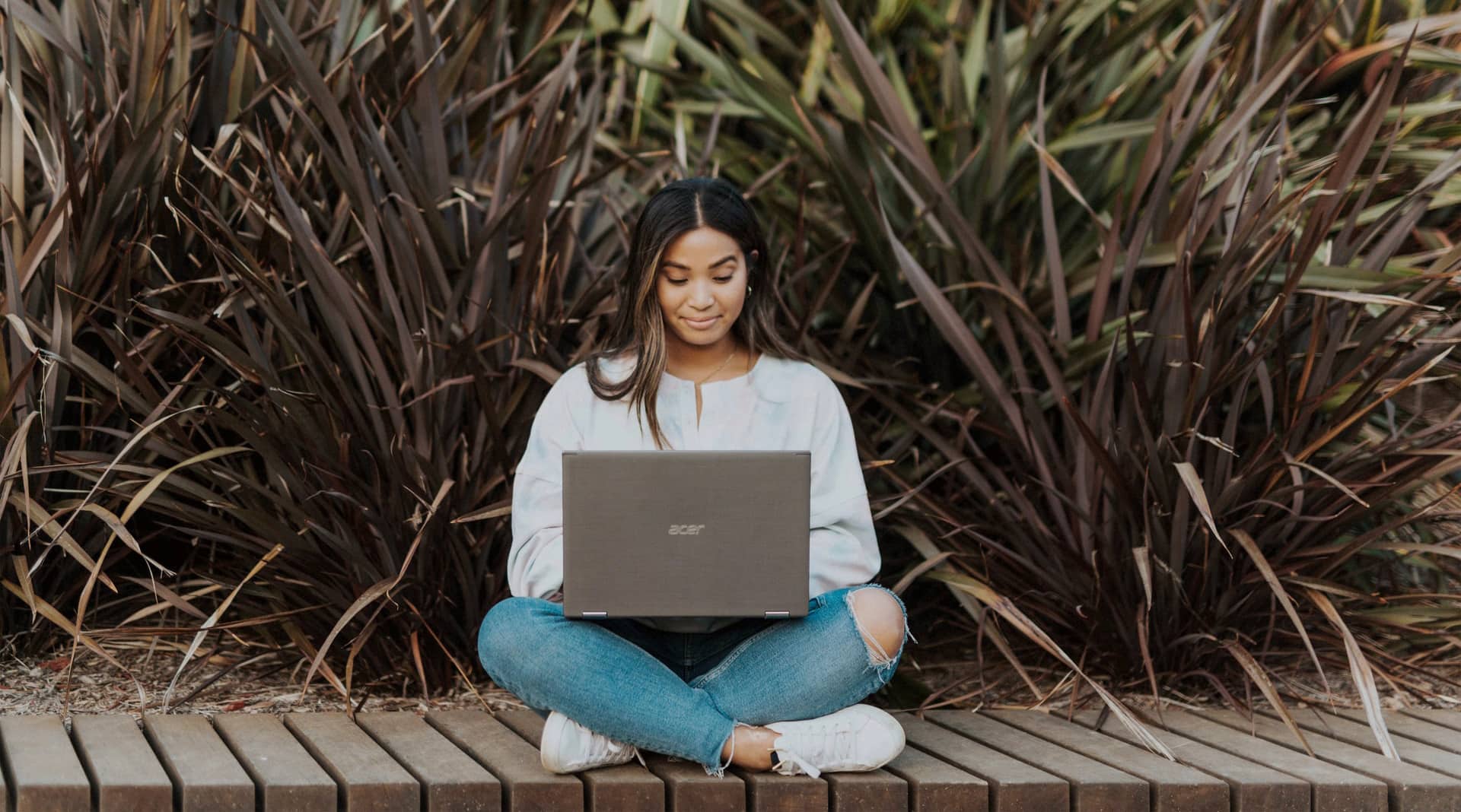 Woman on a laptop sitting by plants