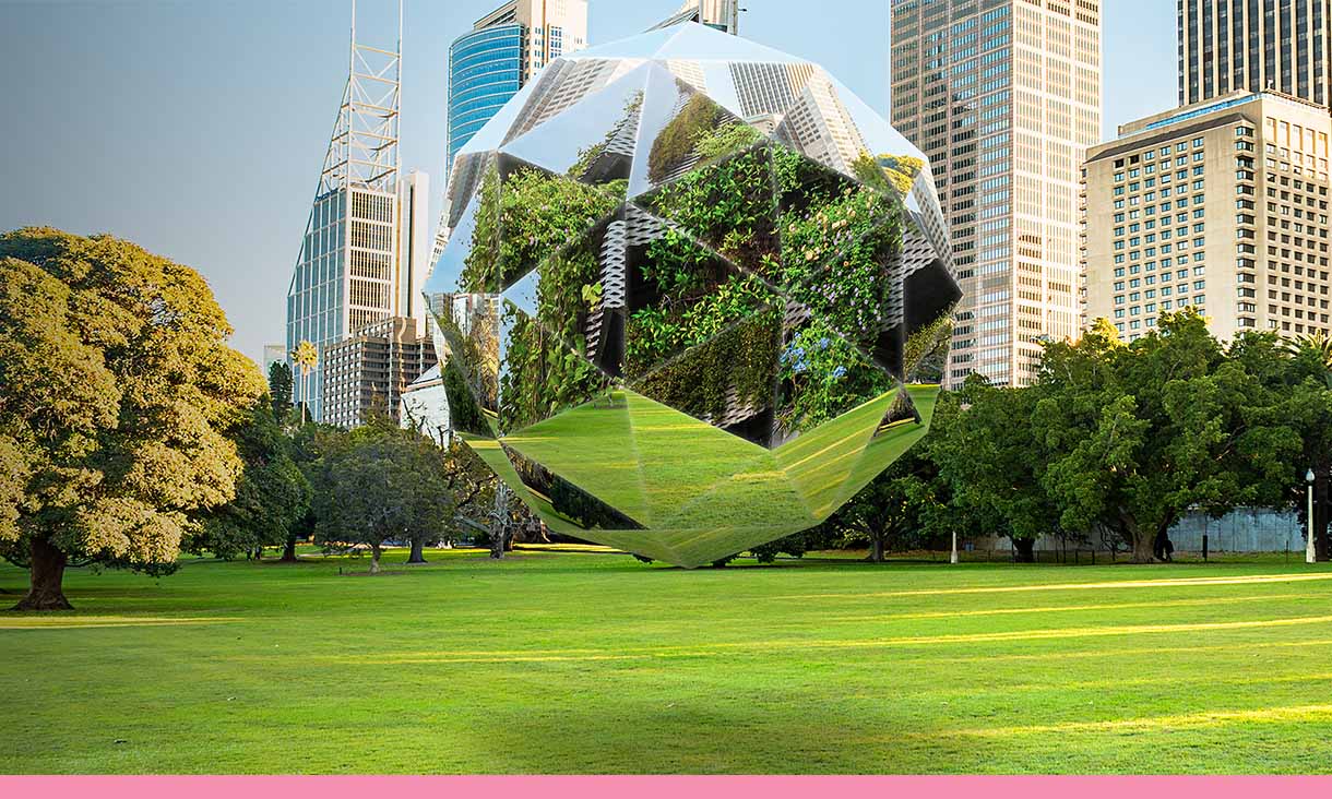 A mirrored multi-sided ball floats in a park with a city in the background.
