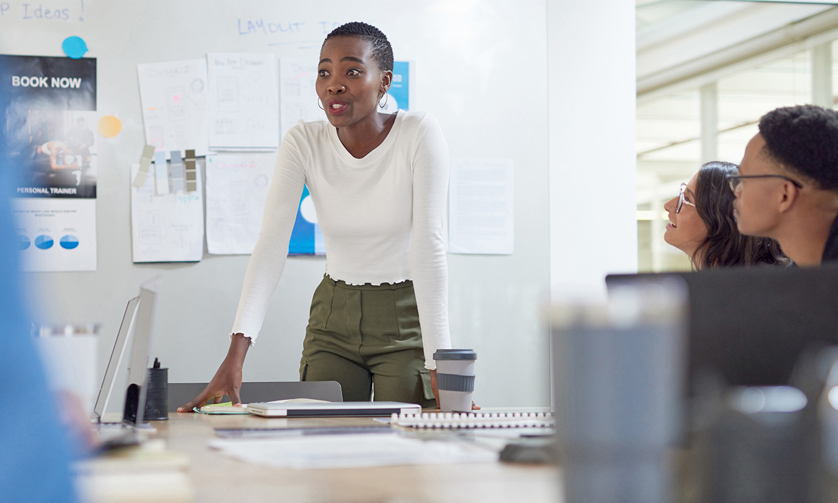 A woman stands and talks in a meeting.